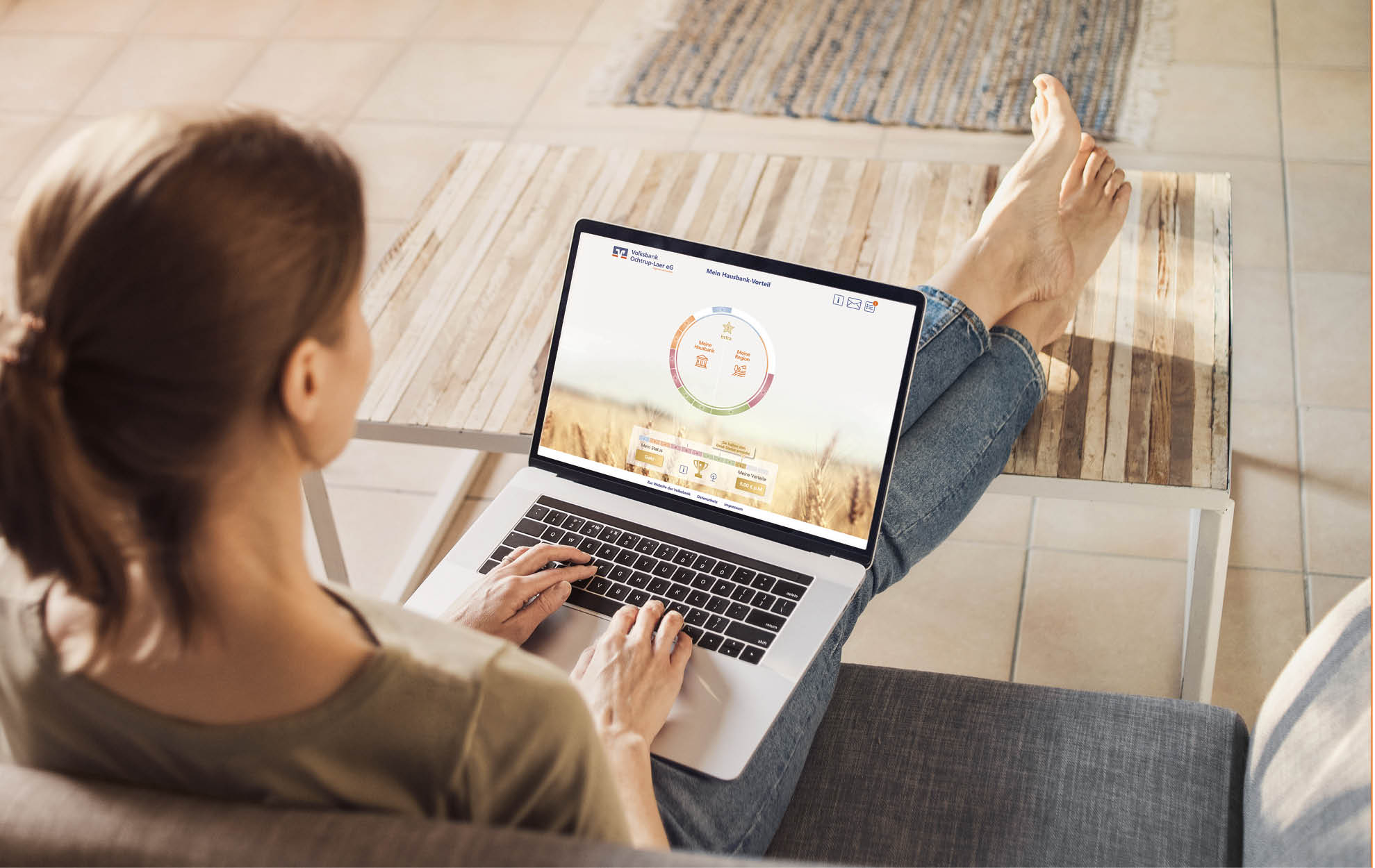 Online-Tool – Volksbank Hausbank-Vorteil Frau sitzt entspannt auf dem Sofa und nutzt auf ihrem Laptop das digitale Hausbank-Tool der Volksbank mit Kreisdiagramm-Anzeige.