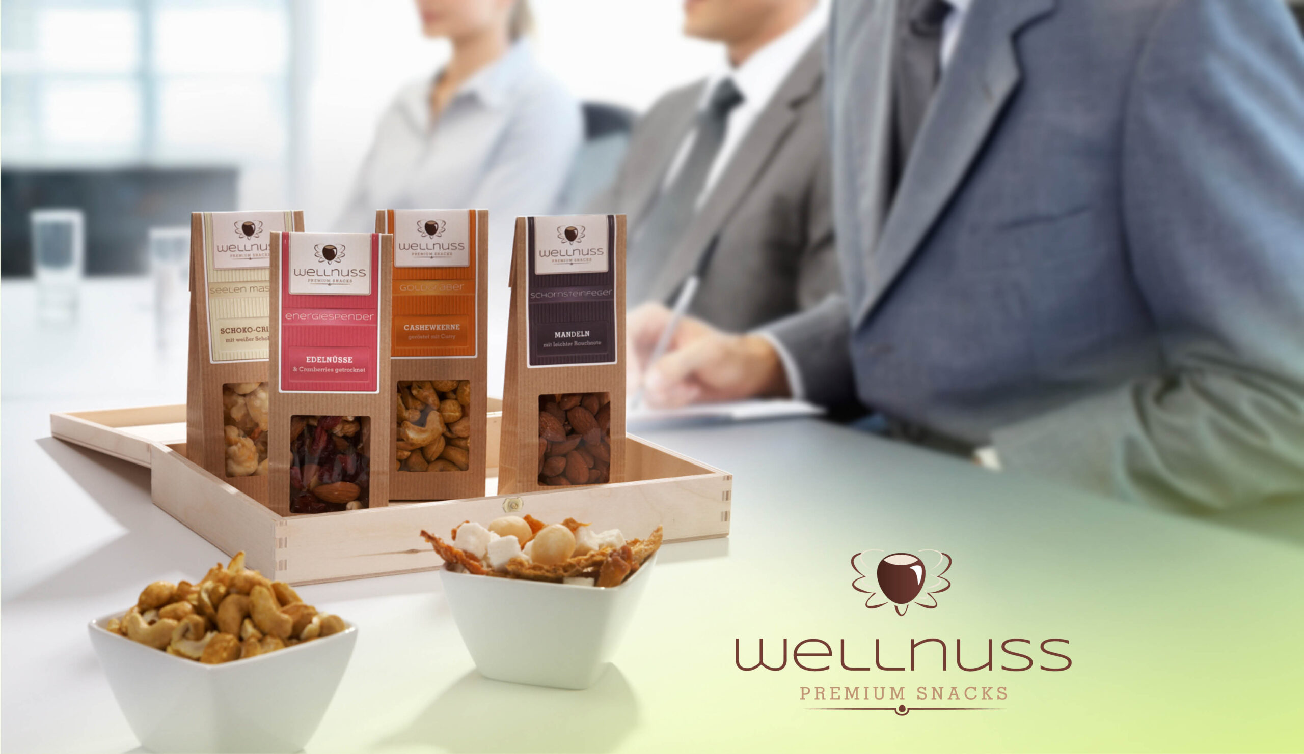 Wellnuss Premium Snacks – stilvolle Produktfotografie mit Snackverpackungen in Holzbox und Servierschalen, präsentiert in einem Business-Kontext.